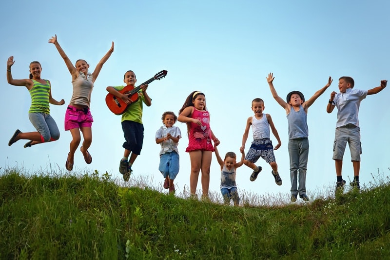 summer camp kids jumping grass